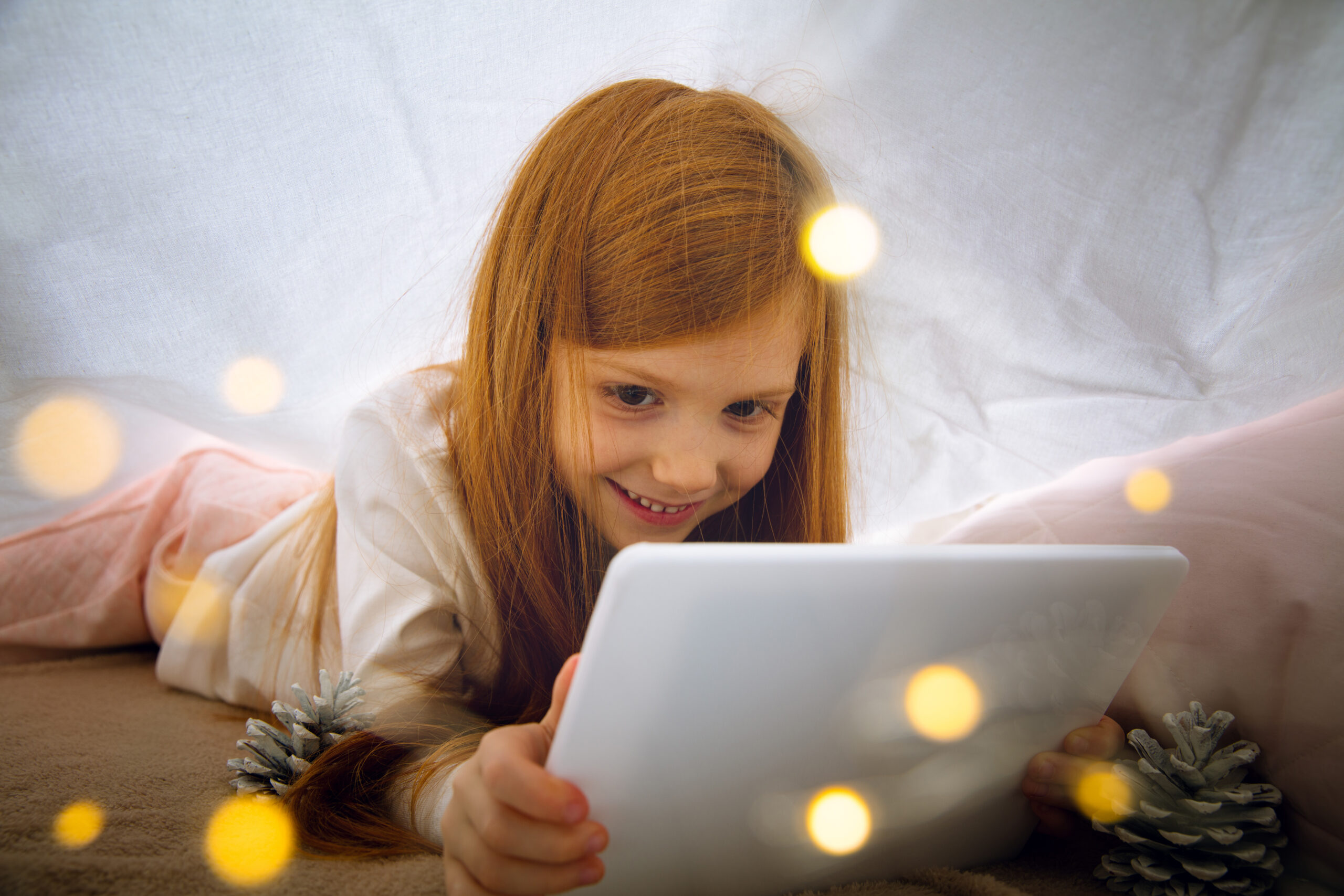 Happy caucasian little girl during video call or messaging with Santa using laptop and home devices